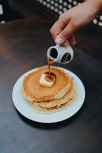 photo of a person pouring syrup on pancake